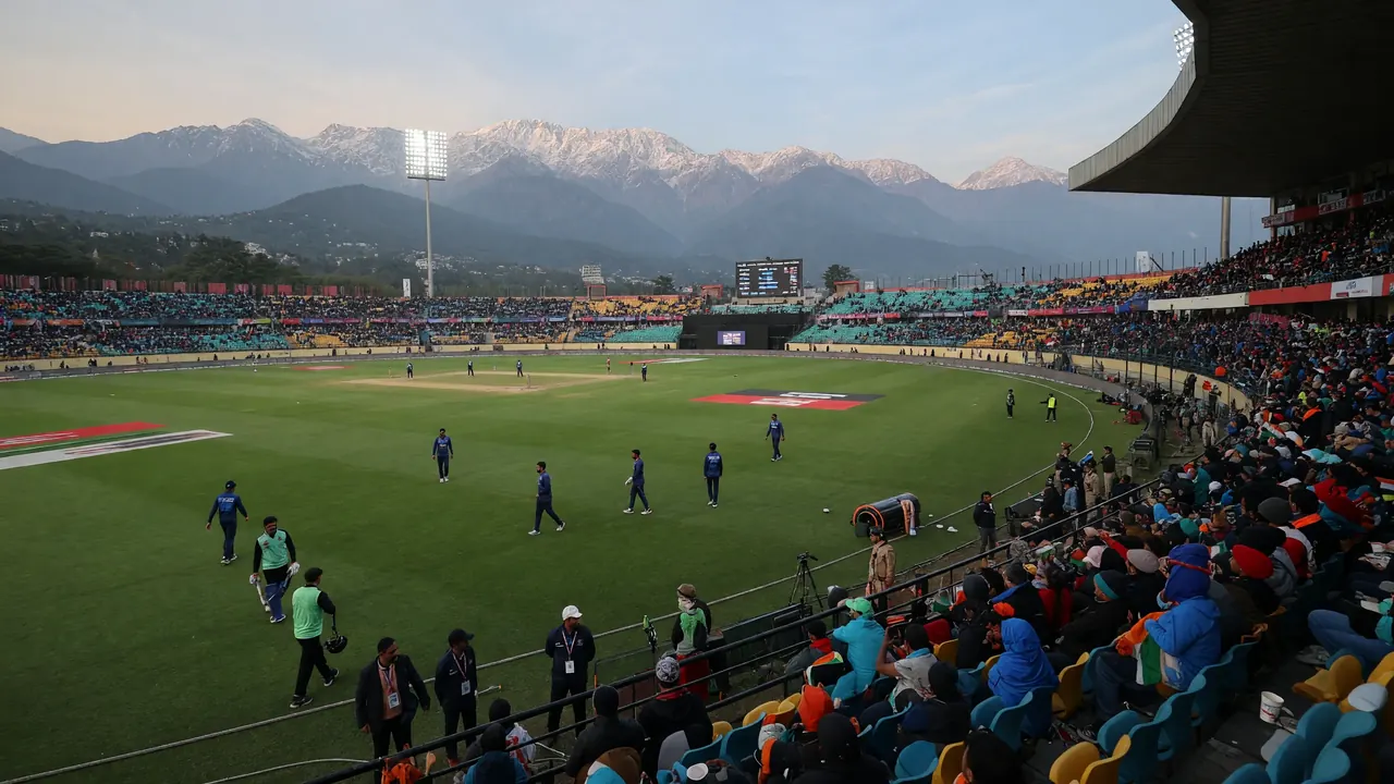 Wide view of a mountain-backed ODI cricket ground with the pitch and crowd seating visible under natural daylight
